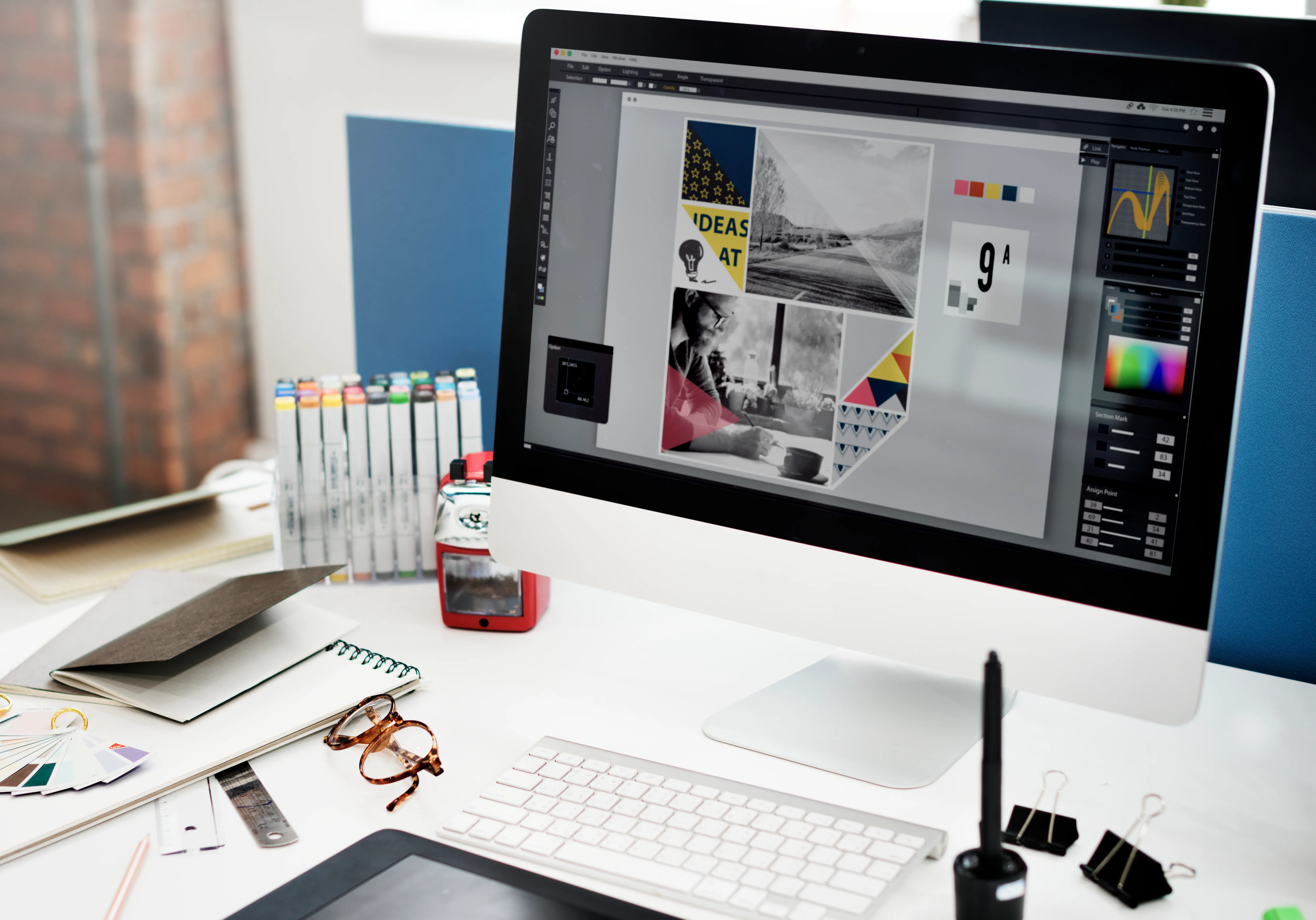 Postazione di grafica con monitor, pennarelli e campionari colore